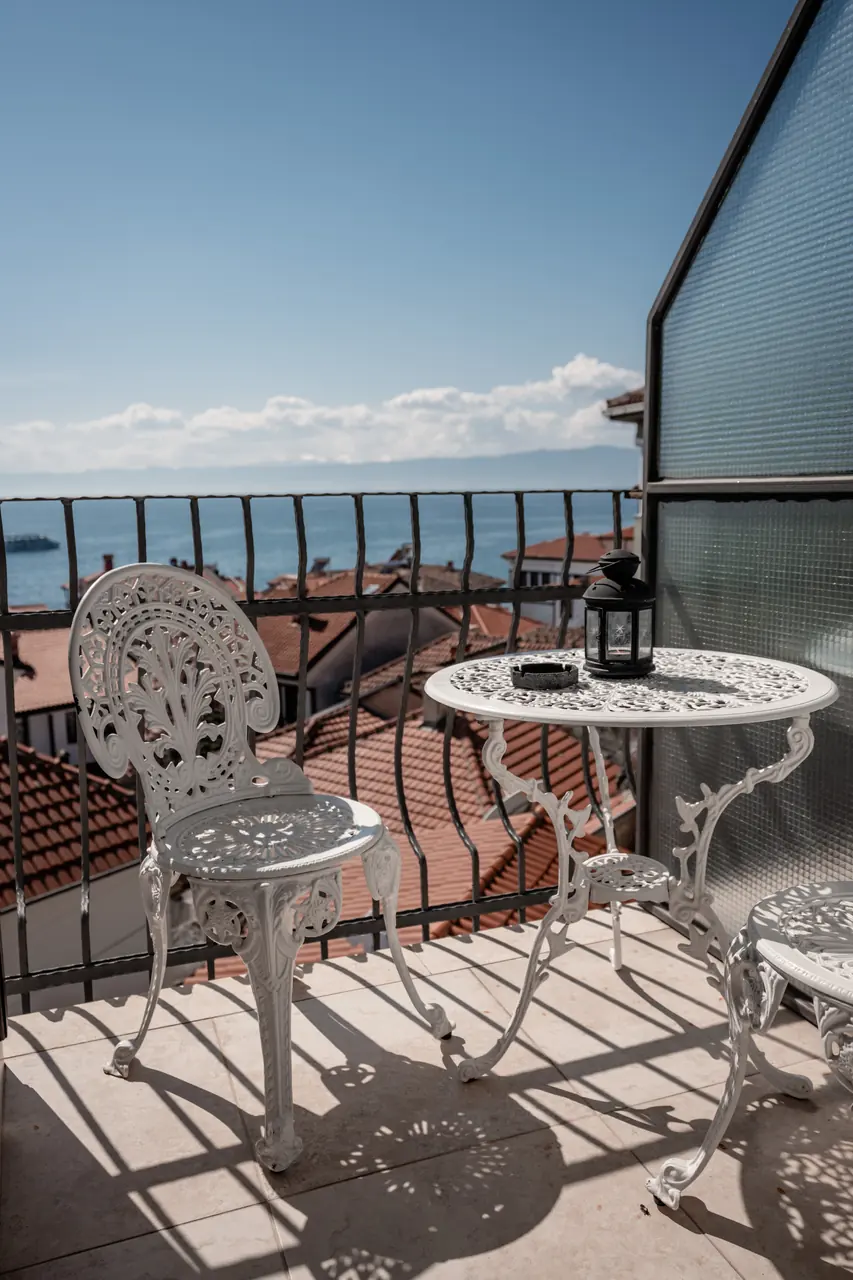 Wrought-iron table and chairs on a balcony looking out over the lake
